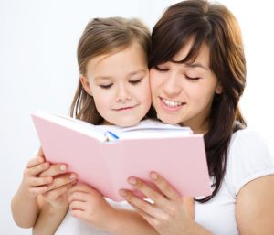 Mother is reading book with her daughter, indoor shoot