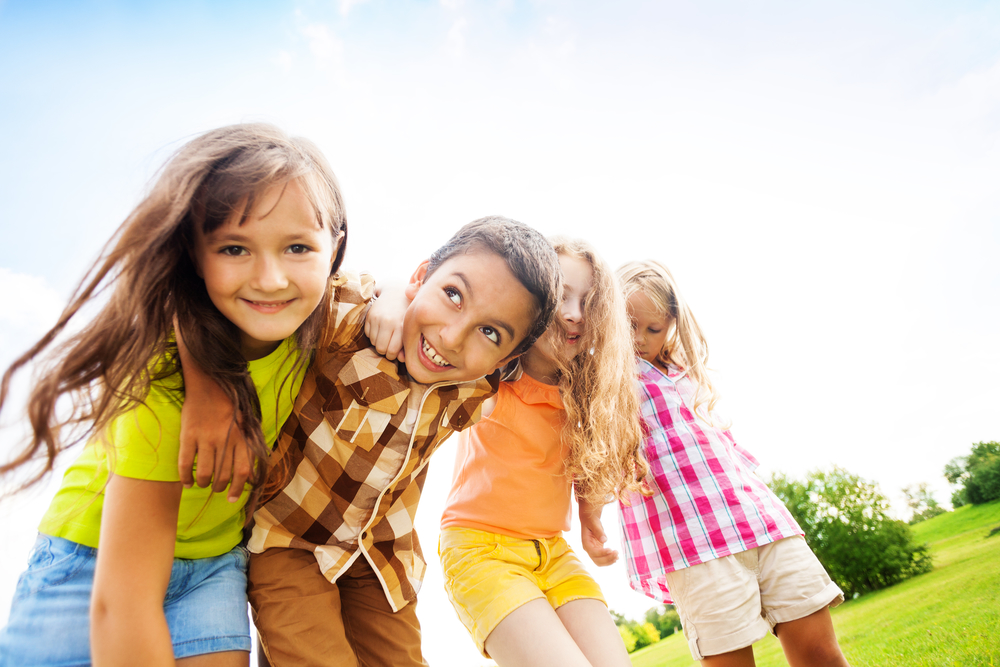 Group of little 6 and 7 years old smiling kids smiling standing outside in the park