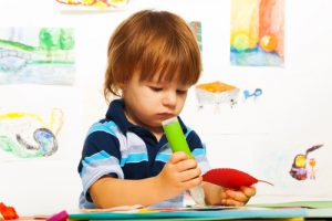 Cute little 2 years old boy in the art  glue color cardboard leaf